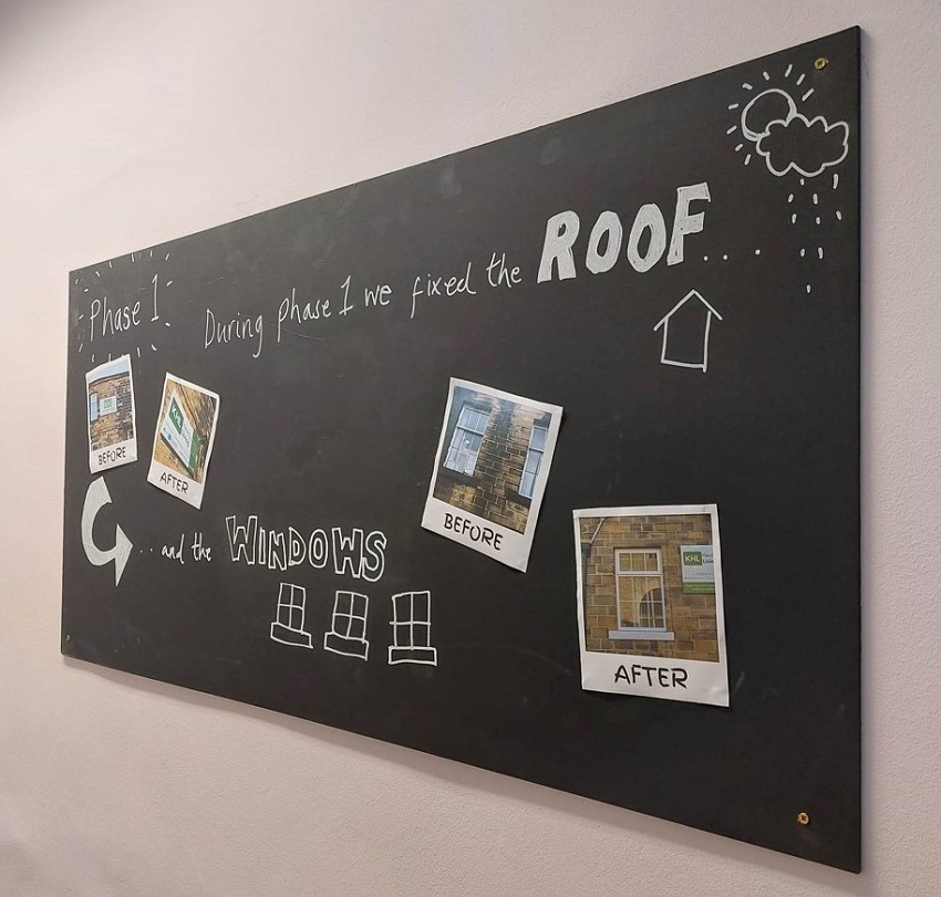 A blackboard with writing on which says "Phase 1: During phase 1 we fixed the roof and the windows".