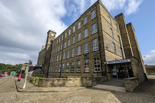 Bradford Industrial Museum - a Victorian mill building surrounded by cobbled streets and with a blue sky behind it.