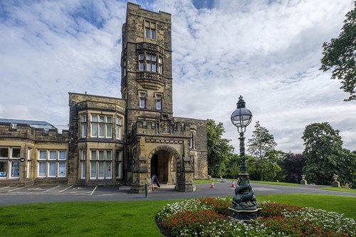 Cliffe Castle museum with flower beds and a lamp post in the foreground.